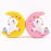 Two squishies. A white unicorn on a yellow half moon and a white unicorn on a pink half moon.