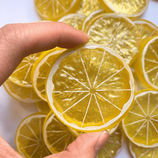 A hand holding a lemon slice charm close up