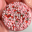  Pink glossy slime with many pink and white round beads, white sprinkles and red strawberry slices sprinkles.