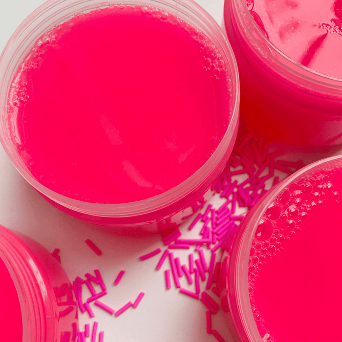 Neon pink clear slimes in their containers with neon pink sprinkles outside