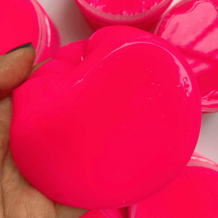 A hand holding a neon pink clear slime