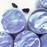 Several blue and purple thick slimes in their containers with two purple grape charms in the background.