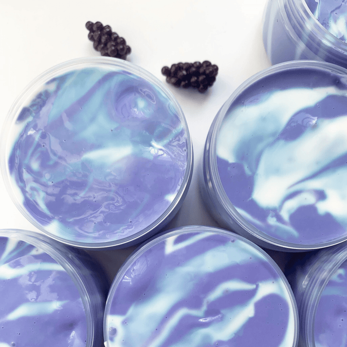 Several blue and purple thick slimes in their containers with two purple grape charms in the background.